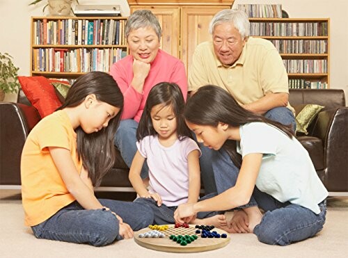 Family with two adults and three children playing a board game on the floor.