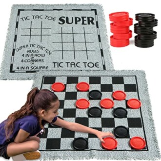 Child playing on a large checkers and tic-tac-toe rug with red and black pieces.